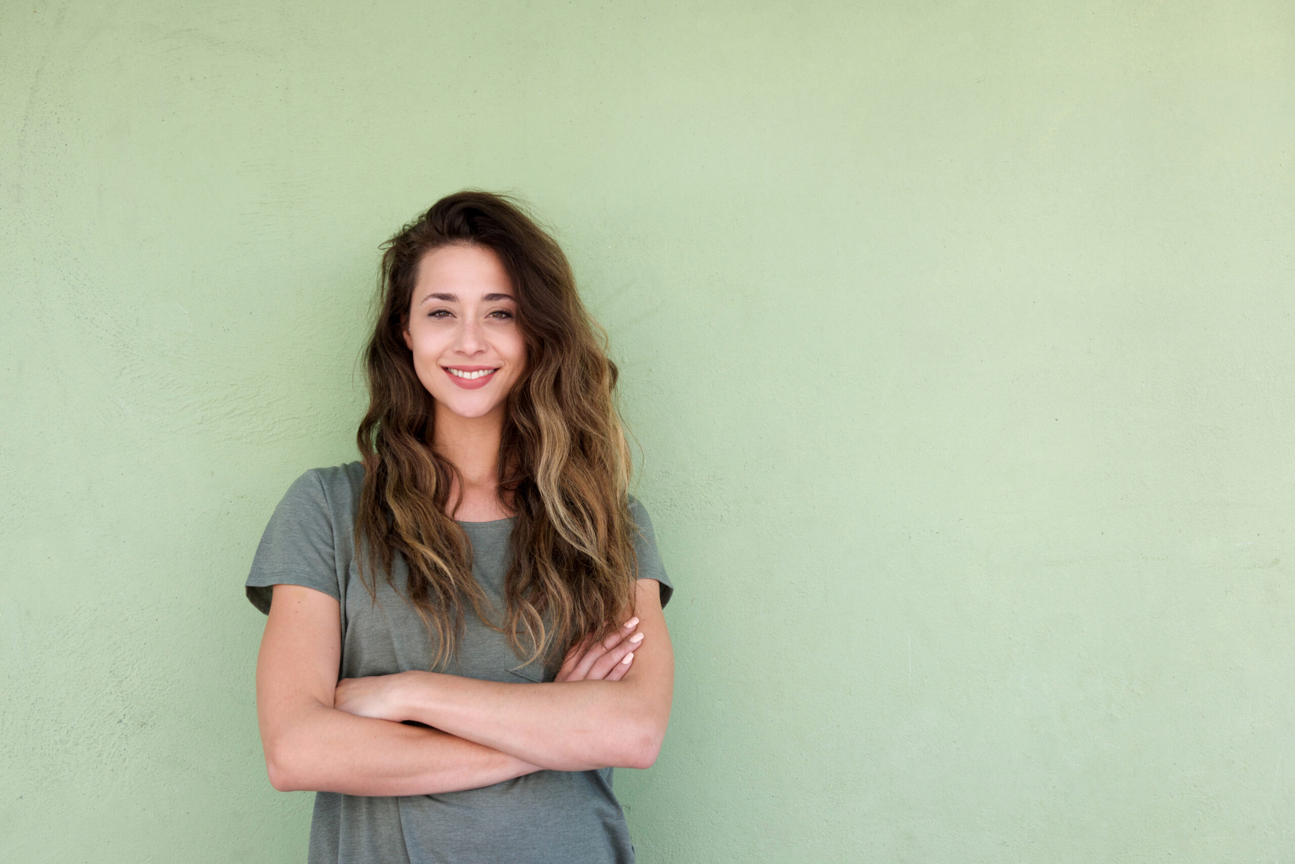 Family Reunion - young smiling woman with arms crossed against green background
